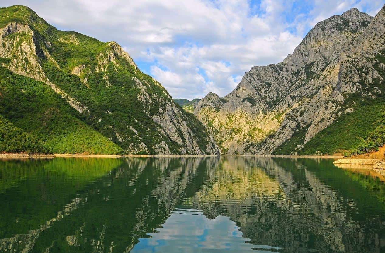 Komana ezers saulrieta laikā ar kalniem fonā